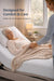 Carer tucking a blanket over an older woman resting on a Visco Therapy mattress on an adjustable bed